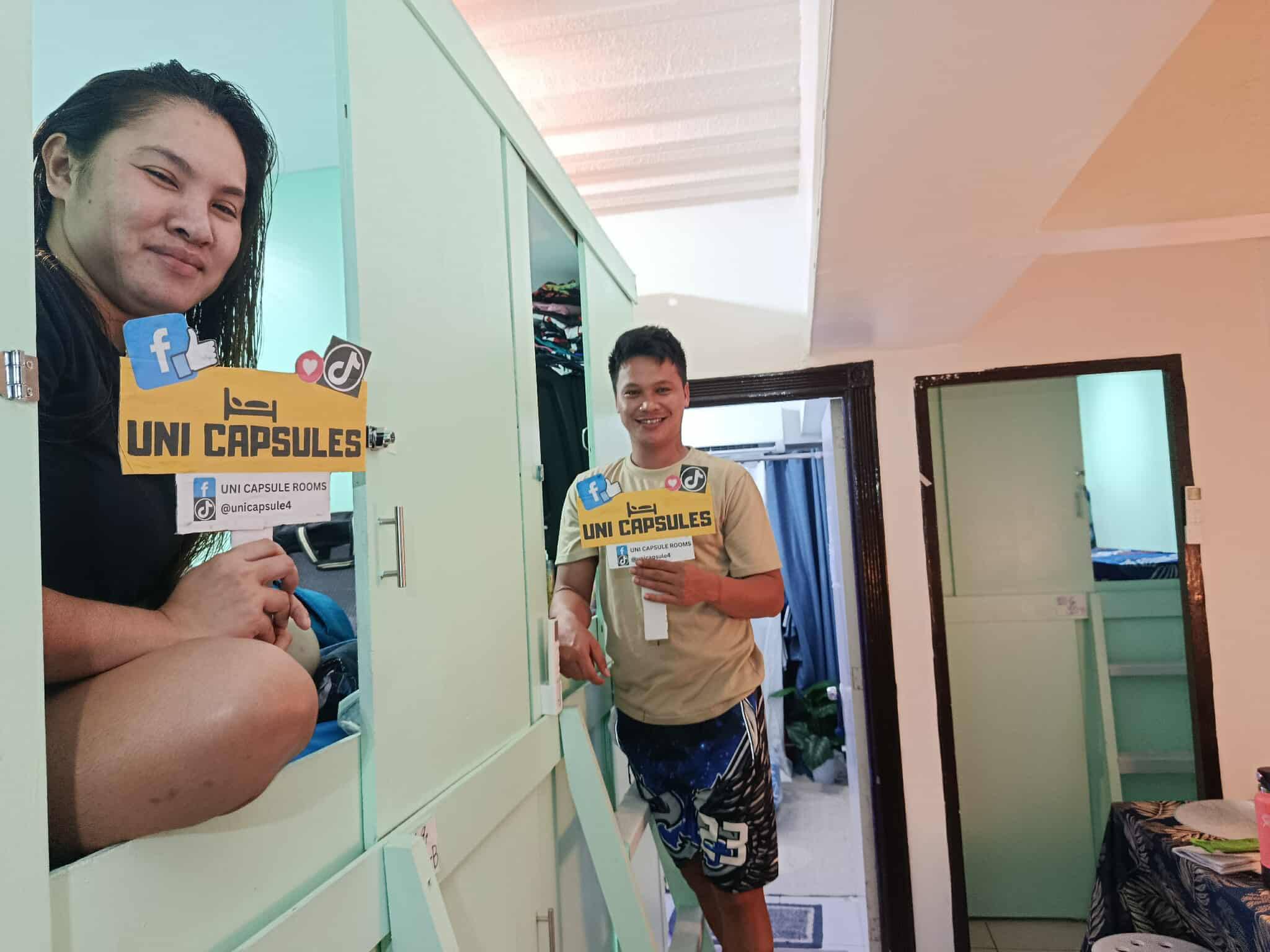 Happy guests holding UniCapsules signs inside the capsule hotel
